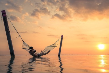 Old man relaxes on the beach next to young couple